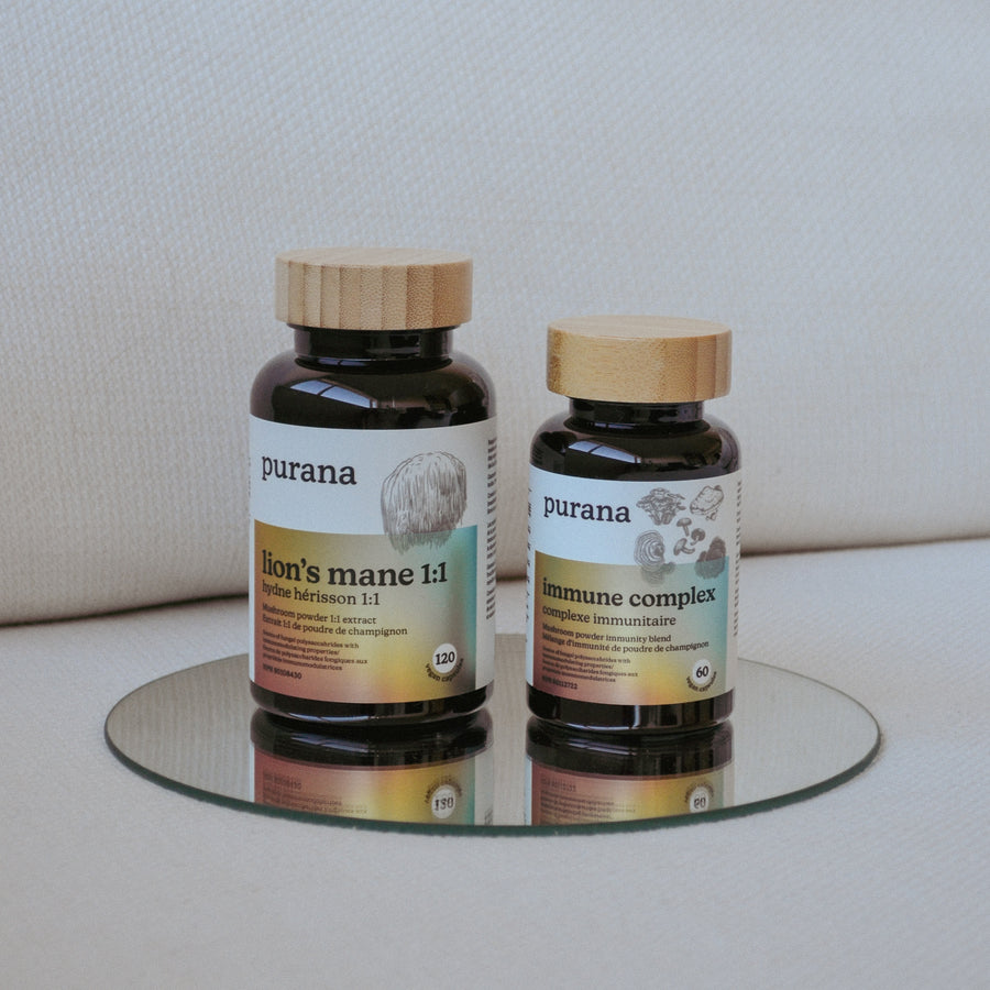 Purana lion's mane 1:1 and immune complex bottles standing on a round mirror against cream linen