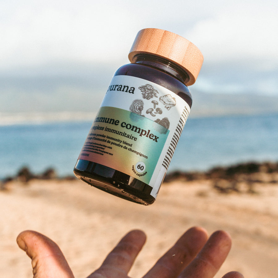 A Purana immune complex bottle tossed in the air above an open hand on a beach
